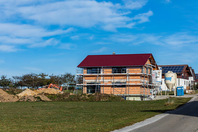 Neu gebautes Haus, das noch eingerüstet ist. Das Haus steht am Ende eines Wohngebiets auf einer grünen Wiese. Der Himmel ist blau. Neu gebautes Haus, das noch eingerüstet ist. Das Haus steht am Ende eines Wohngebiets auf einer grünen Wiese. Der Himmel ist blau.