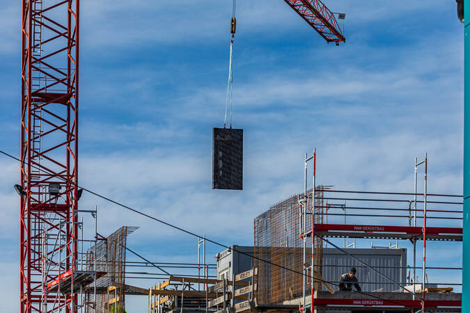 Ein Haus im Rohbau, das eingerüstet ist. Im linken Bildbereich befindet sich ein roten Kran, welcher gerade Material an die Baustelle befördert. Ein Haus im Rohbau, das eingerüstet ist. Im linken Bildbereich befindet sich ein roten Kran, welcher gerade Material an die Baustelle befördert.