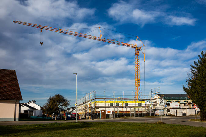 Ein gelber Baukran bei einer Baustelle für ein Haus. Ein gelber Baukran bei einer Baustelle für ein Haus.
