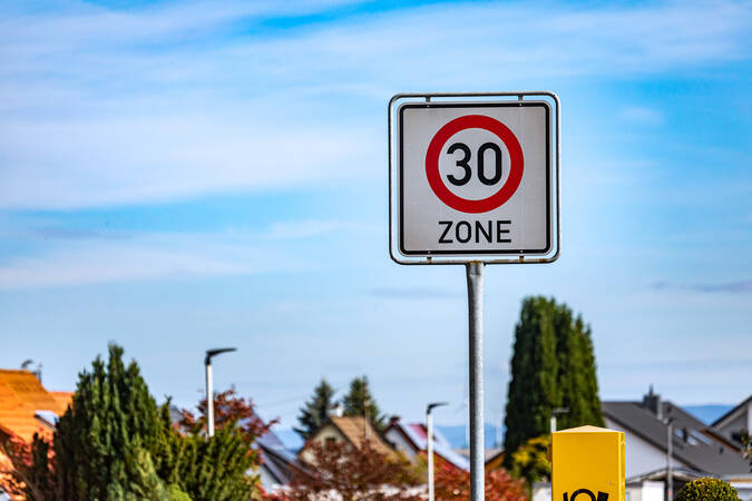 Ein Verkehrsschild, das auf den Beginn einer Tempo-30-Zone hinweist vor einem blauen Himmel. Ein Verkehrsschild, das auf den Beginn einer Tempo-30-Zone hinweist vor einem blauen Himmel.